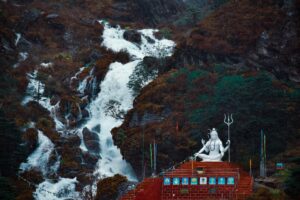 Serene landscape of a Himalayan temple beside a flowing waterfall, capturing spiritual and natural beauty.