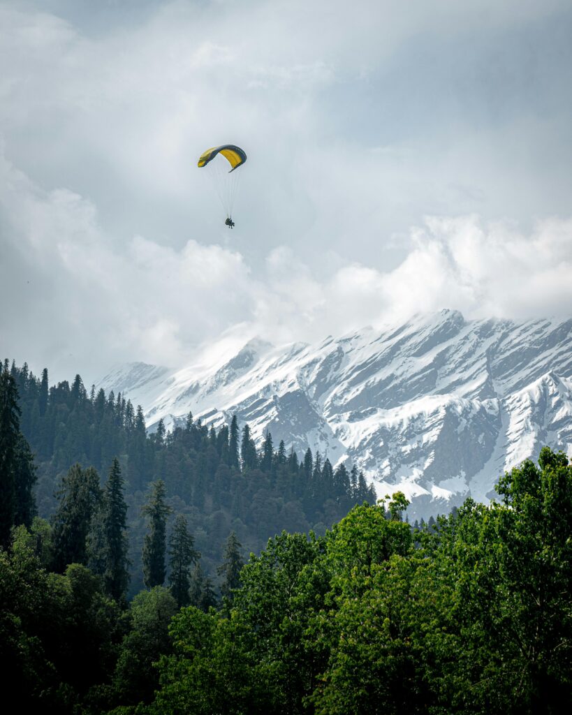 Experience the thrill of paragliding above the snowy mountains of Solang Valley, India. A breathtaking adventure awaits.