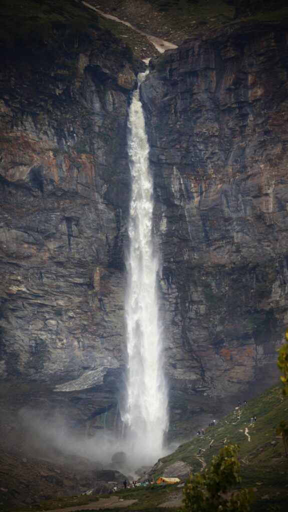 Stunning shot of a tall waterfall cascading down rocky cliffs in Manali, India.