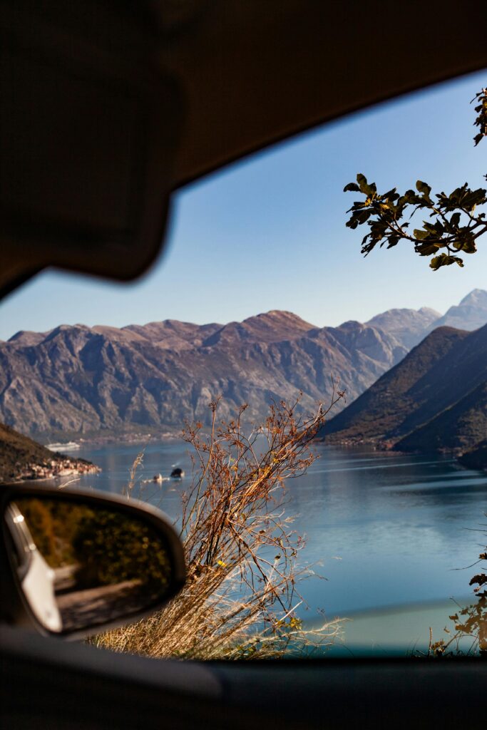 Stunning view of a tranquil mountain lake framed by car window, capturing serenity of nature.