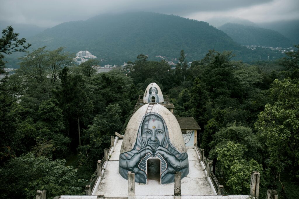 From above small domed caves with graffiti on Buddhist meditation house rooftop located in Beatles Ashram in lush green rainforest against cloudy sky in India