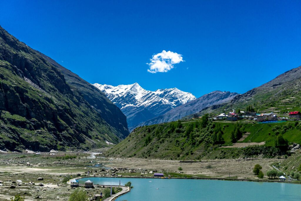 Captivating view of Jispa valley with snow-capped peaks and a serene lake under a clear blue sky.