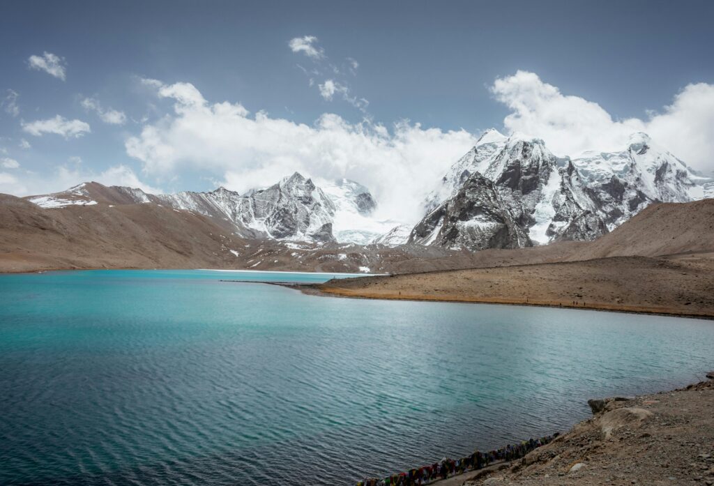 Stunning view of Gurudongmar Lake with snow-covered mountains in Sikkim, India.