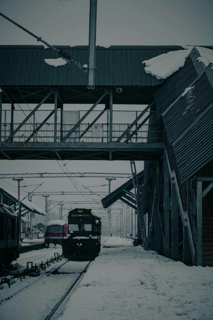 Snow-covered train station with passenger train in Mirgund during winter.