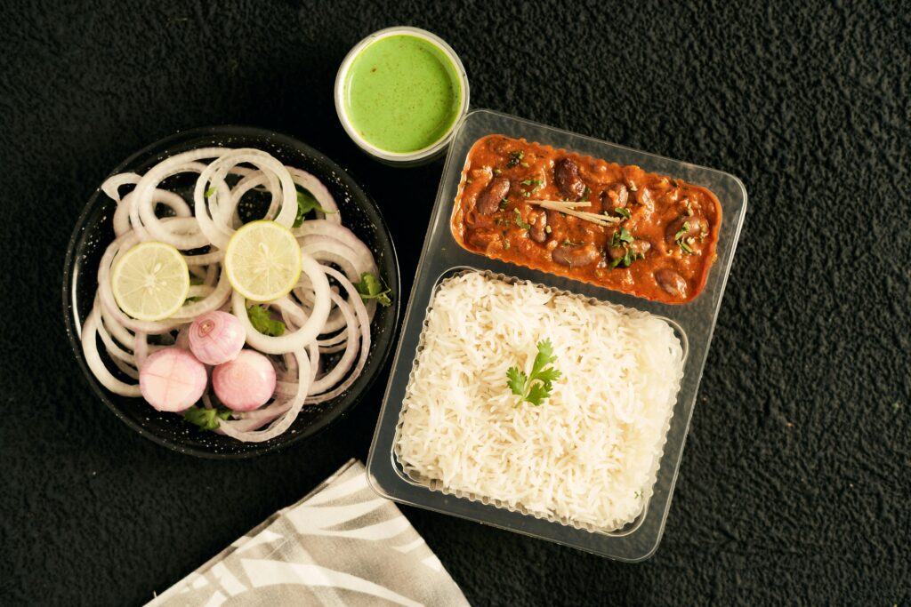 Delicious Indian meal featuring rajma curry, basmati rice, and onion salad with green chutney.