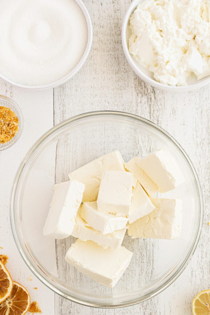 Top view of cream cheese and ingredients for a fresh dish on white wooden table.