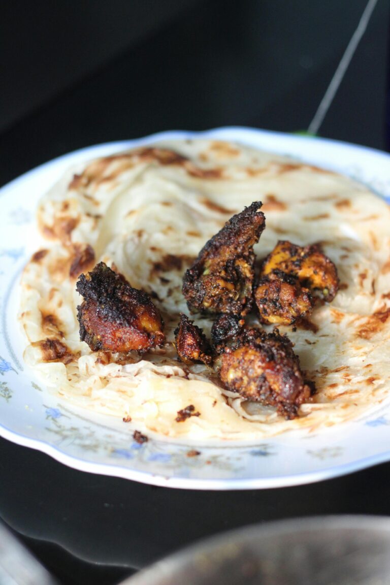 Close-up of Kerala parotta and grilled chicken served on a plate, showcasing authentic Indian cuisine.