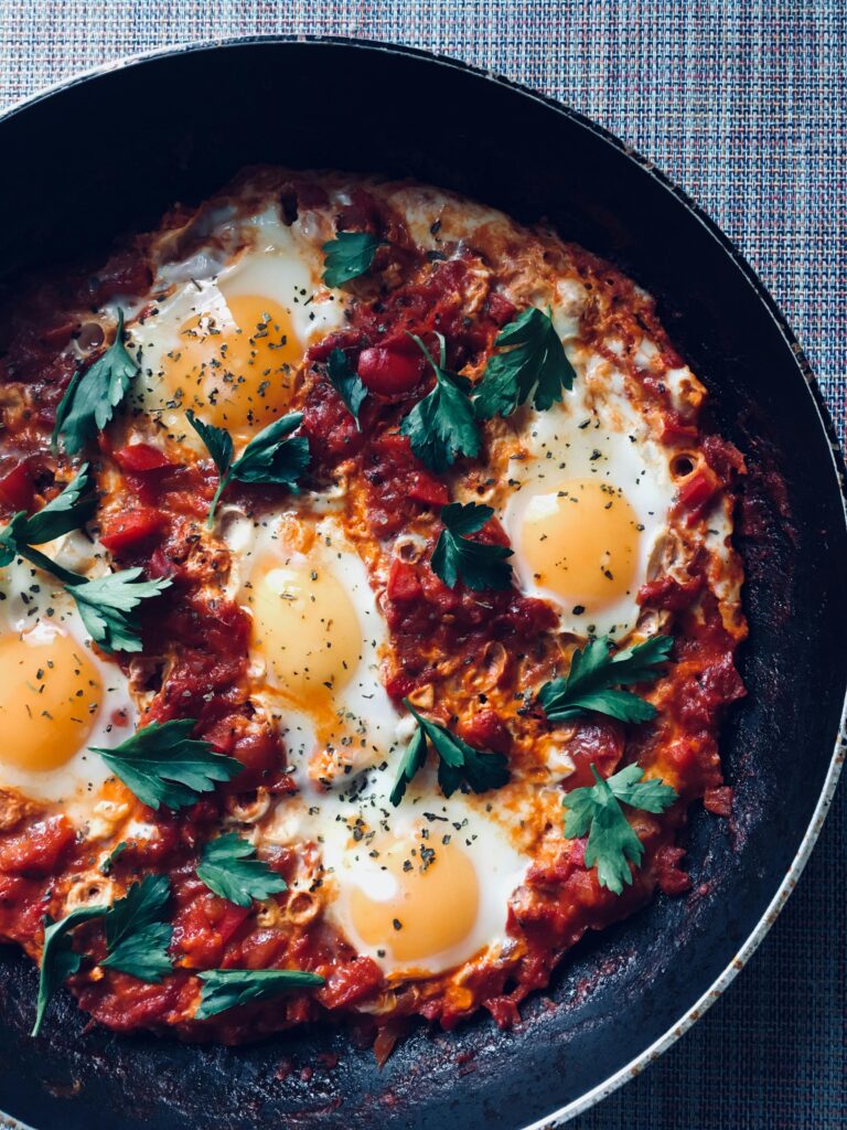 Close-up of a flavorful shakshuka with eggs, tomatoes, and herbs, perfect for a hearty breakfast or brunch.