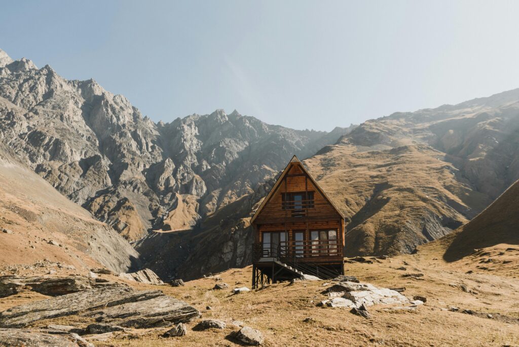 Cozy wooden cabin amidst majestic mountain peaks and rugged nature.