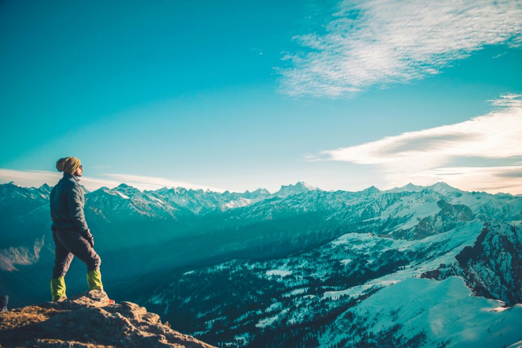 Man standing on Himalayan peak, enjoying snowy landscape and blue sky in the winter.