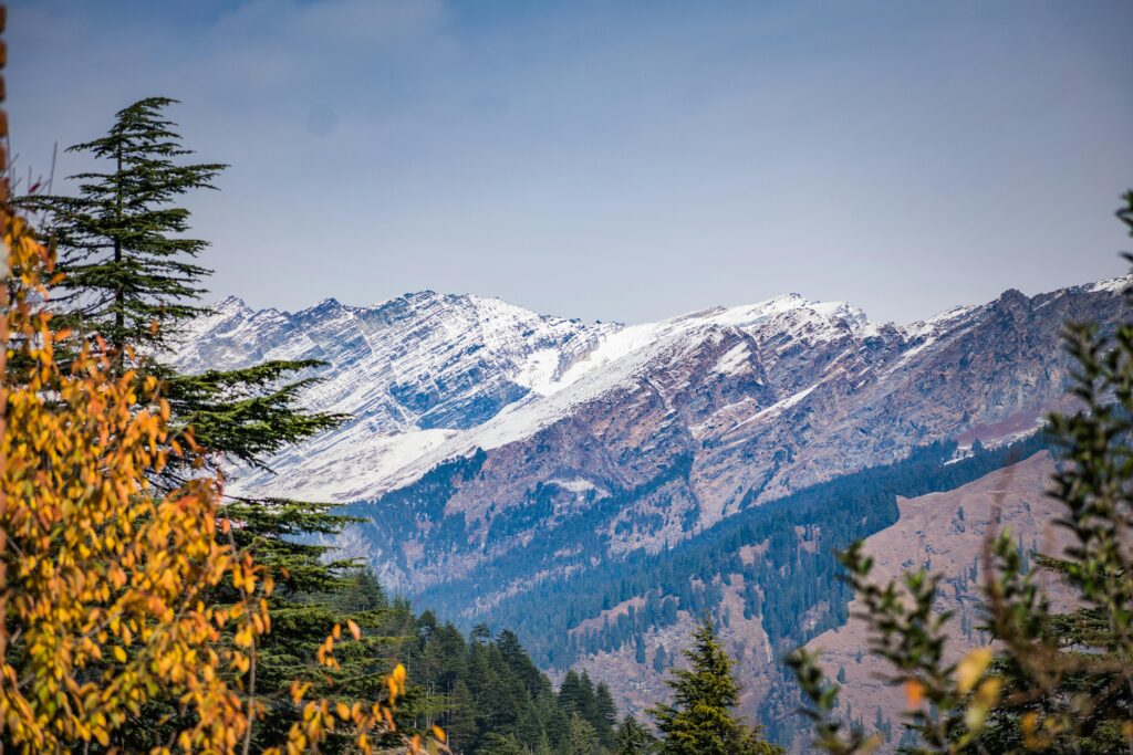 Breathtaking view of snow-covered Himalayas with autumn foliage in Manali, India.