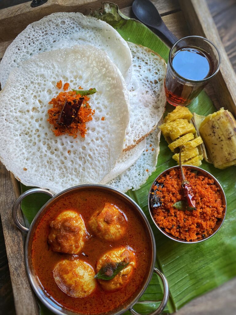 Delicious South Indian breakfast served on a banana leaf with appam, curry, and chutney.