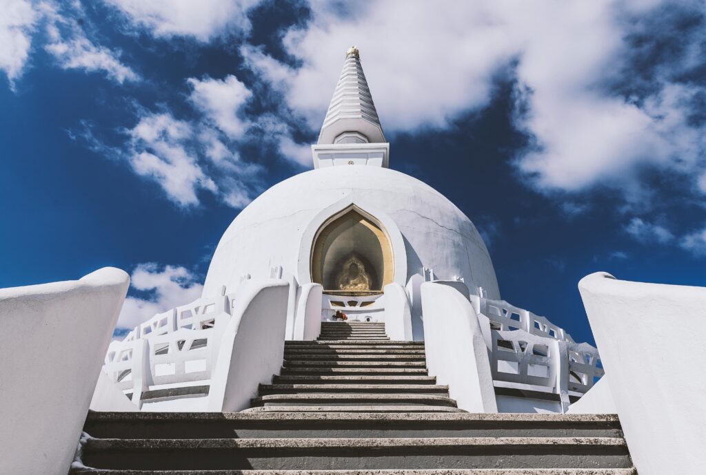 A peaceful stupa with traditional architecture set against a vibrant blue sky, symbolizing spirituality and serenity at darjeeling